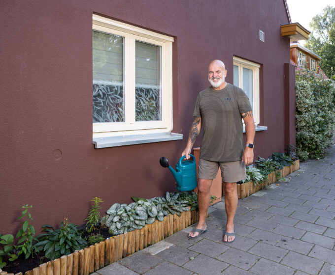 Man met gieter bij geveltuin blij met tuin en Tegelservice Amsterdam Weerproof