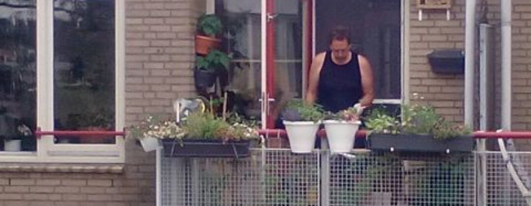 Man op groen balkon met planten voor regenopvang Amsterdam Weerproof