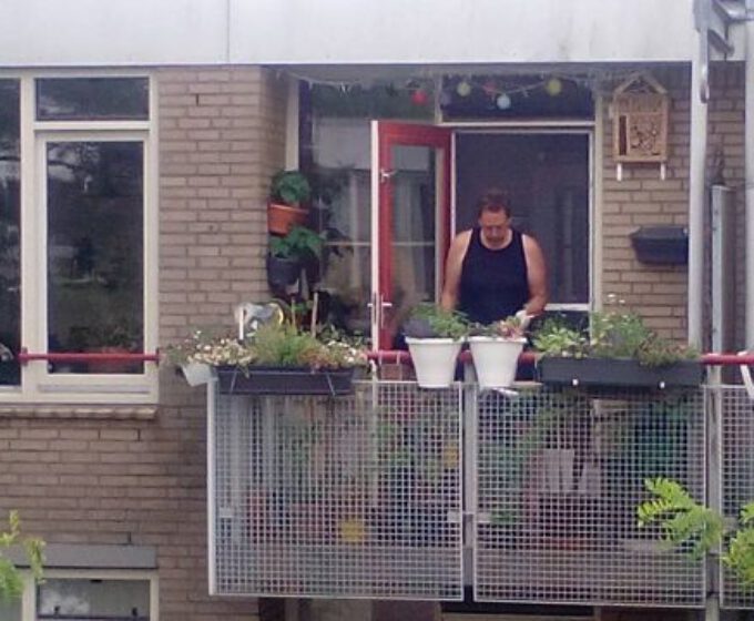 Man op groen balkon met planten voor regenopvang Amsterdam Weerproof
