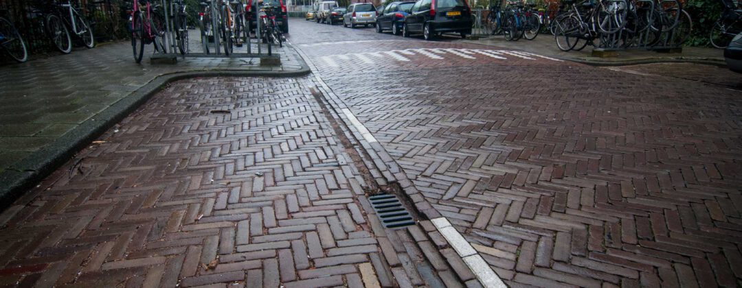 Holle weg bij parkeerplaats stuurt regenwater richting riool Amsterdam Weerproof