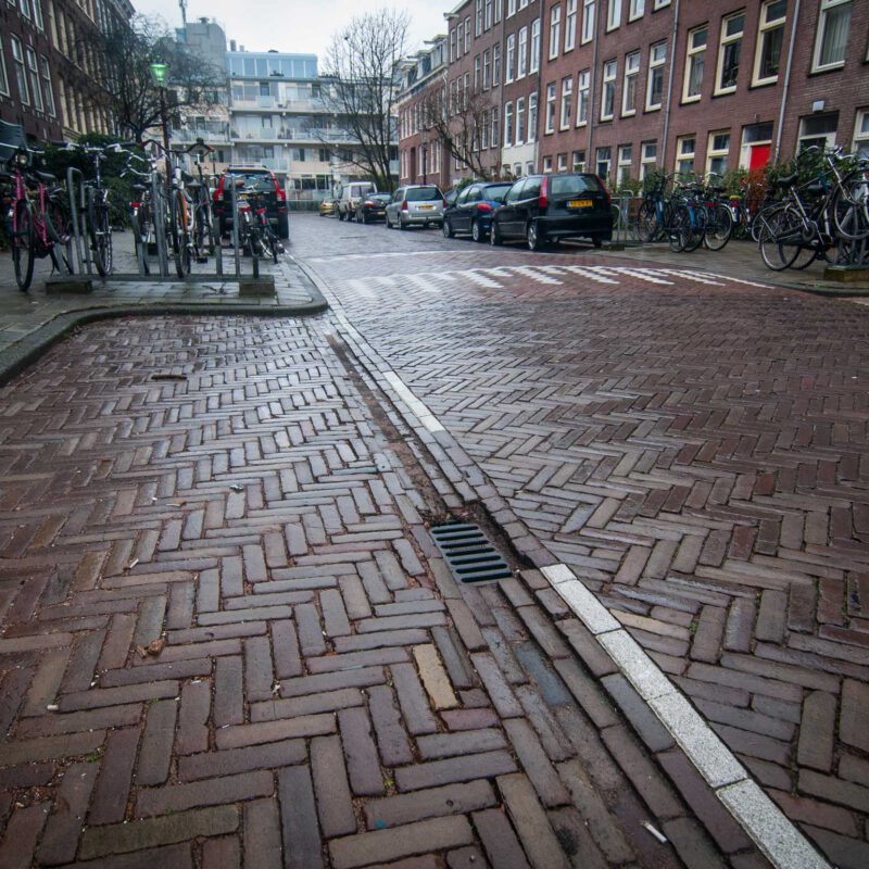 Holle weg bij parkeerplaats stuurt regenwater richting riool Amsterdam Weerproof