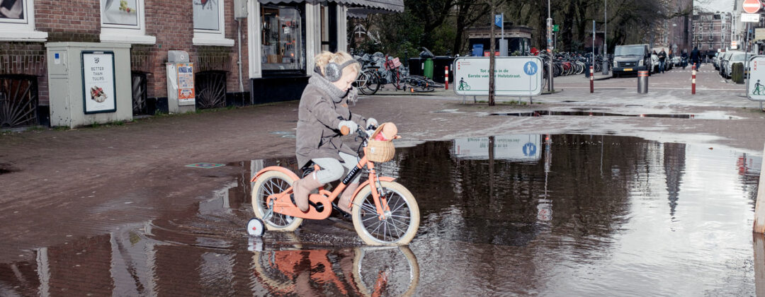Meisje fietst door plas in Amsterdam Weerproof