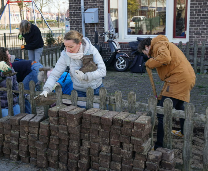 Vrijwilliger werkt aan tuin bij de Heggerankweg Amsterdam Weerproof