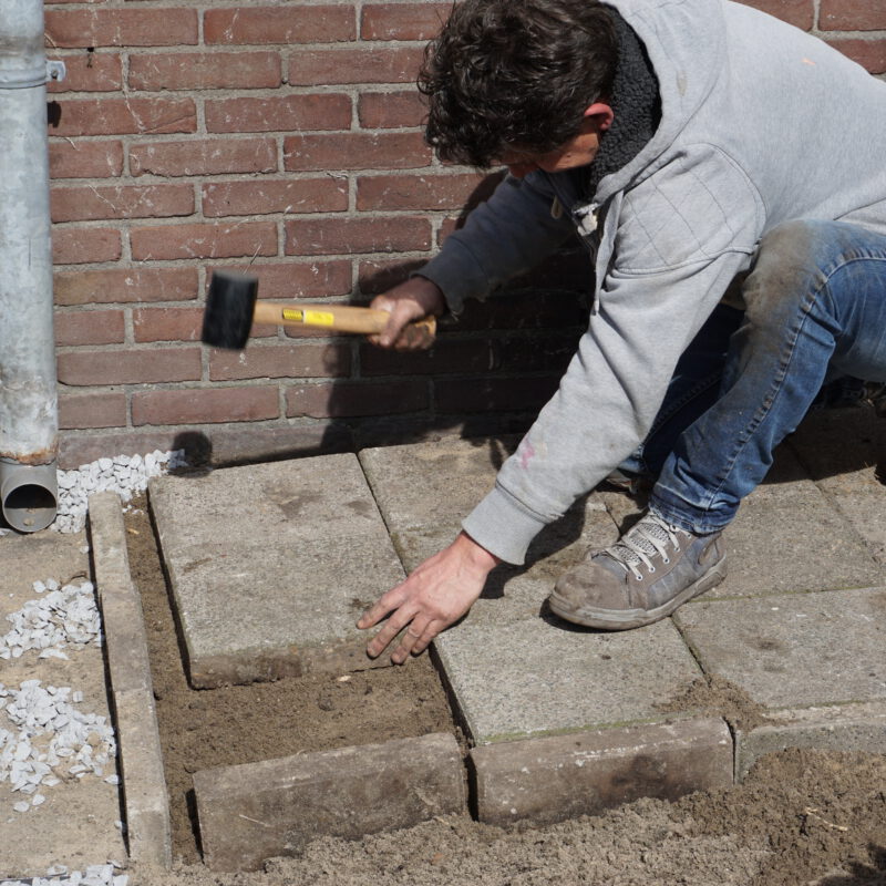 Vrijwilliger werkt aan tuin bij de Heggerankweg Amsterdam Weerproof