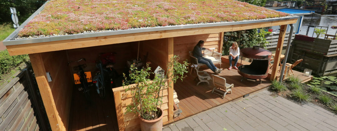 Mensen onder groen dak op schuur bij woonboot Amsterdam Weerproof