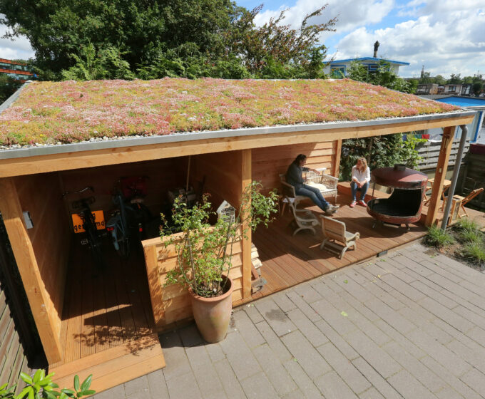 Mensen onder groen dak op schuur bij woonboot Amsterdam Weerproof