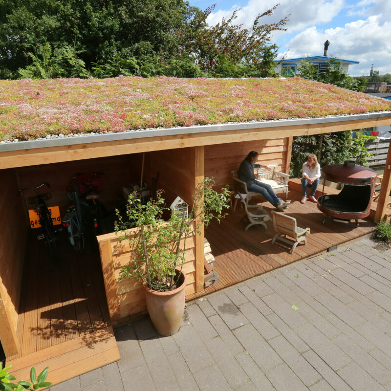 Mensen onder groen dak op schuur bij woonboot Amsterdam Weerproof