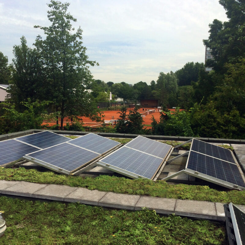 Groen dak en zonnepanelen tegen extreme neerslag met uitzicht op tennisveld Amsterdam Weerproof