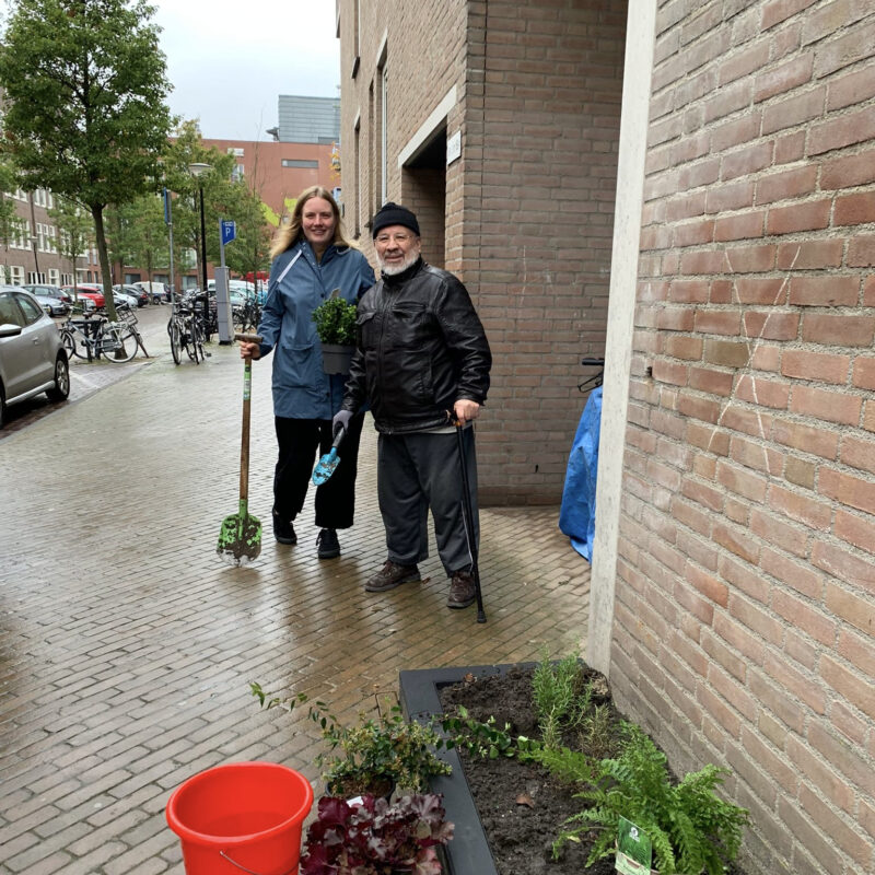 Men en vrouw met schep leggen geveltuin aan bij woning Eigen Haard Amsterdam Weerproof