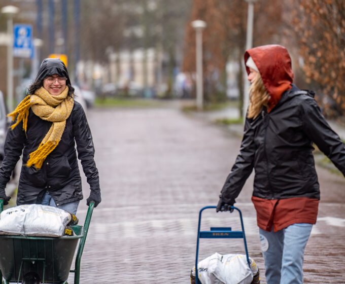 Vrijwilligers vervoeren zakken aarde in de regen Amsterdam Weerproof