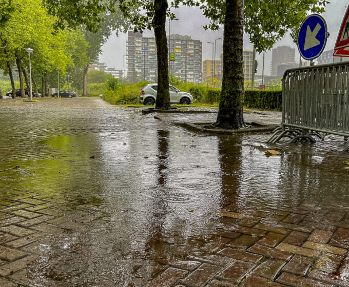 Grote plas met regendruppels op parkeerplaats Amsterdam Weerproof